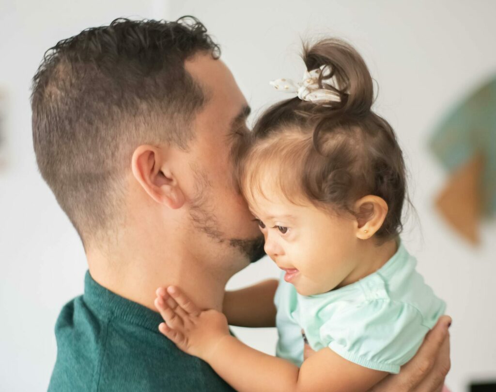 A father holds his daughter as he chats on the phone with a consultation service provider about transitioning to CFSS.