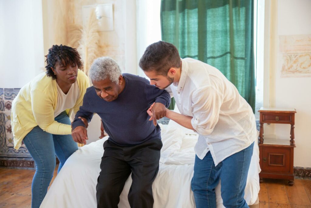 Two caregivers help an elderly man enrolled in ICF residential services.