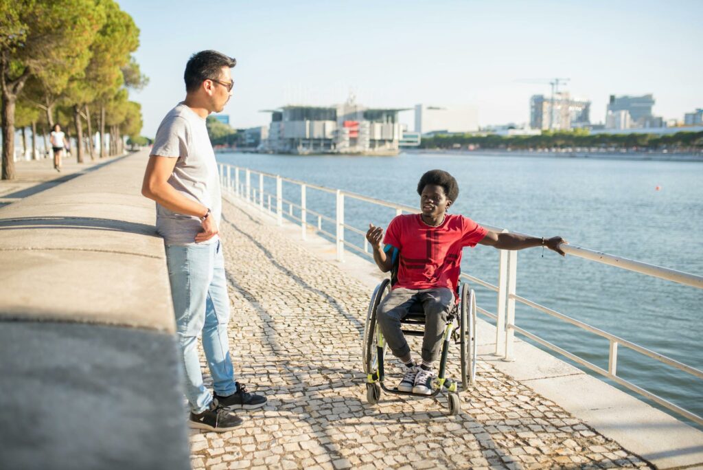 Two roommates from a residential services community home chat together beside a dock in the city.