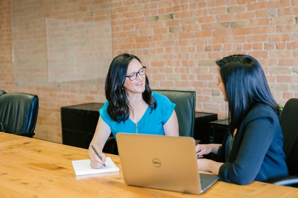 Two consultants sit side by side talking about how to best approach a client's CFSS Service Delivery Plan.